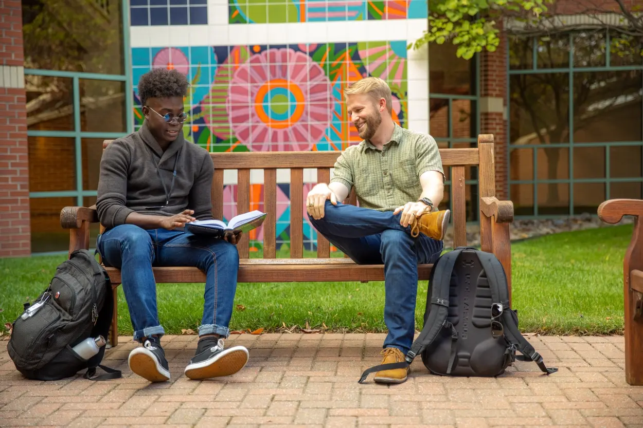 Two students talking on bench in OSU-Tulsa Courtyard.