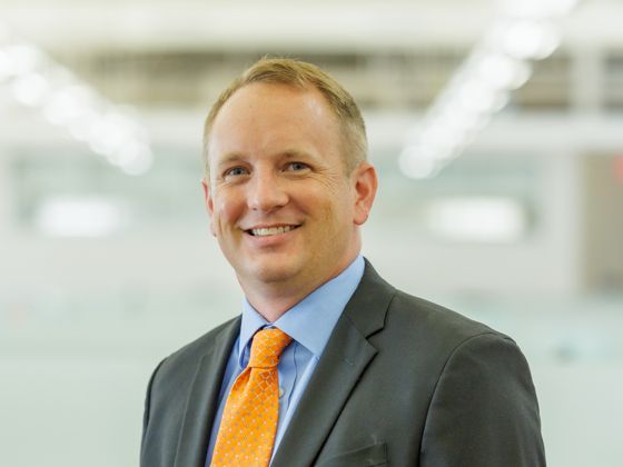 Man wearing a black suit with an orange tie