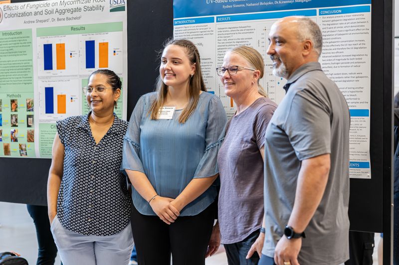 People pose in front of their poster