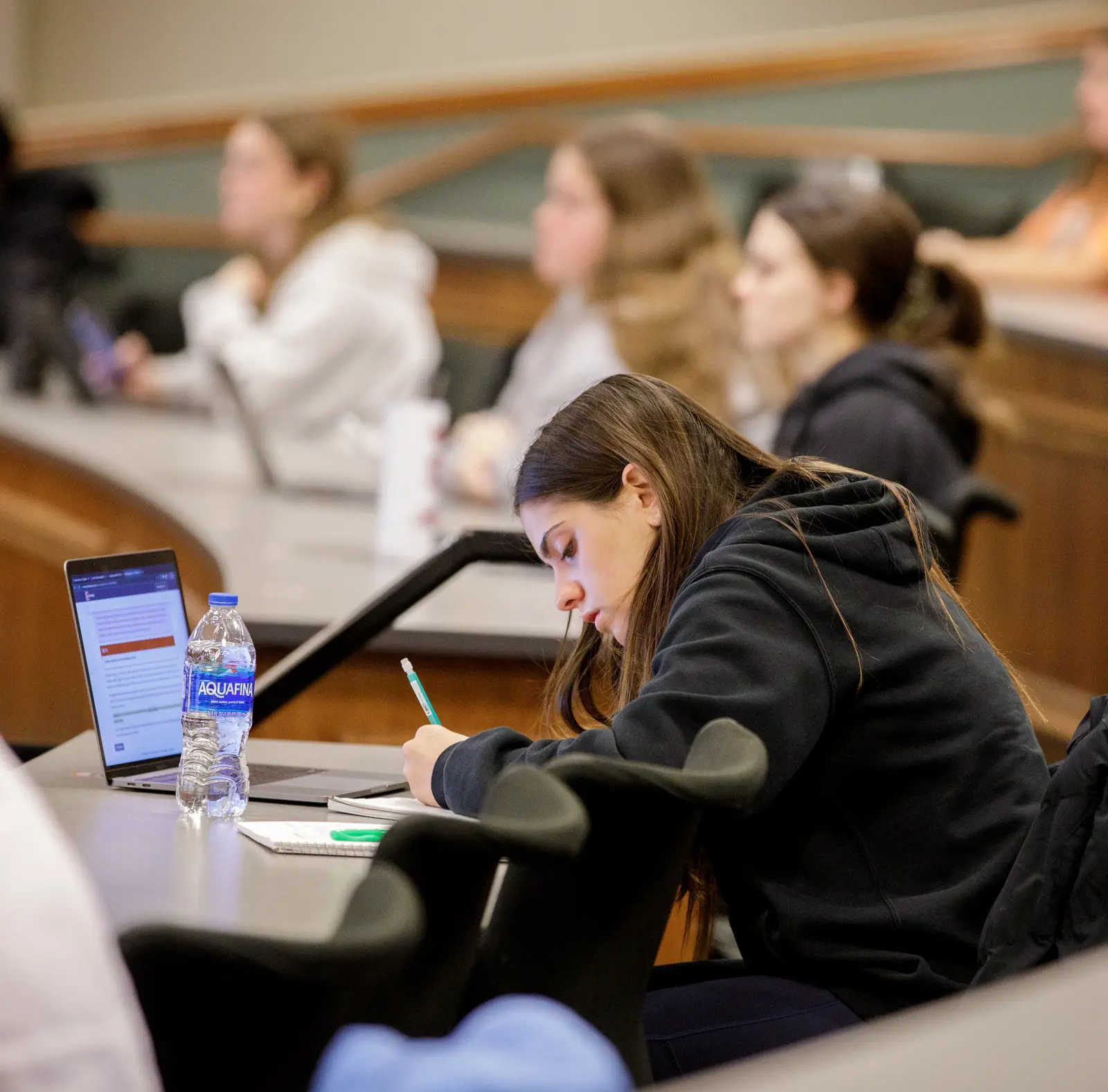 A female student takes notes in class.