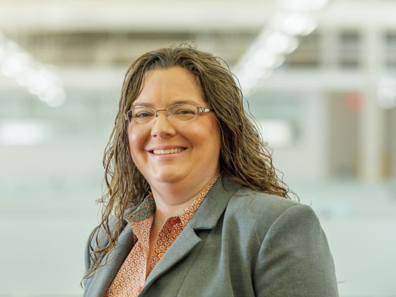 Woman wearing a orange collared shirt with a gray suit jacket