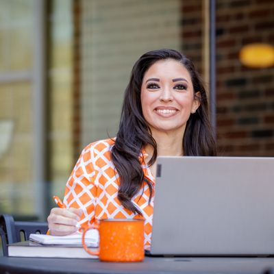 Well dressed student sits behind a laptop with pen in hand ready to start an online process.