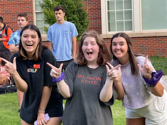 3 girls hold "go pokes" hands up as they smile at the camera.