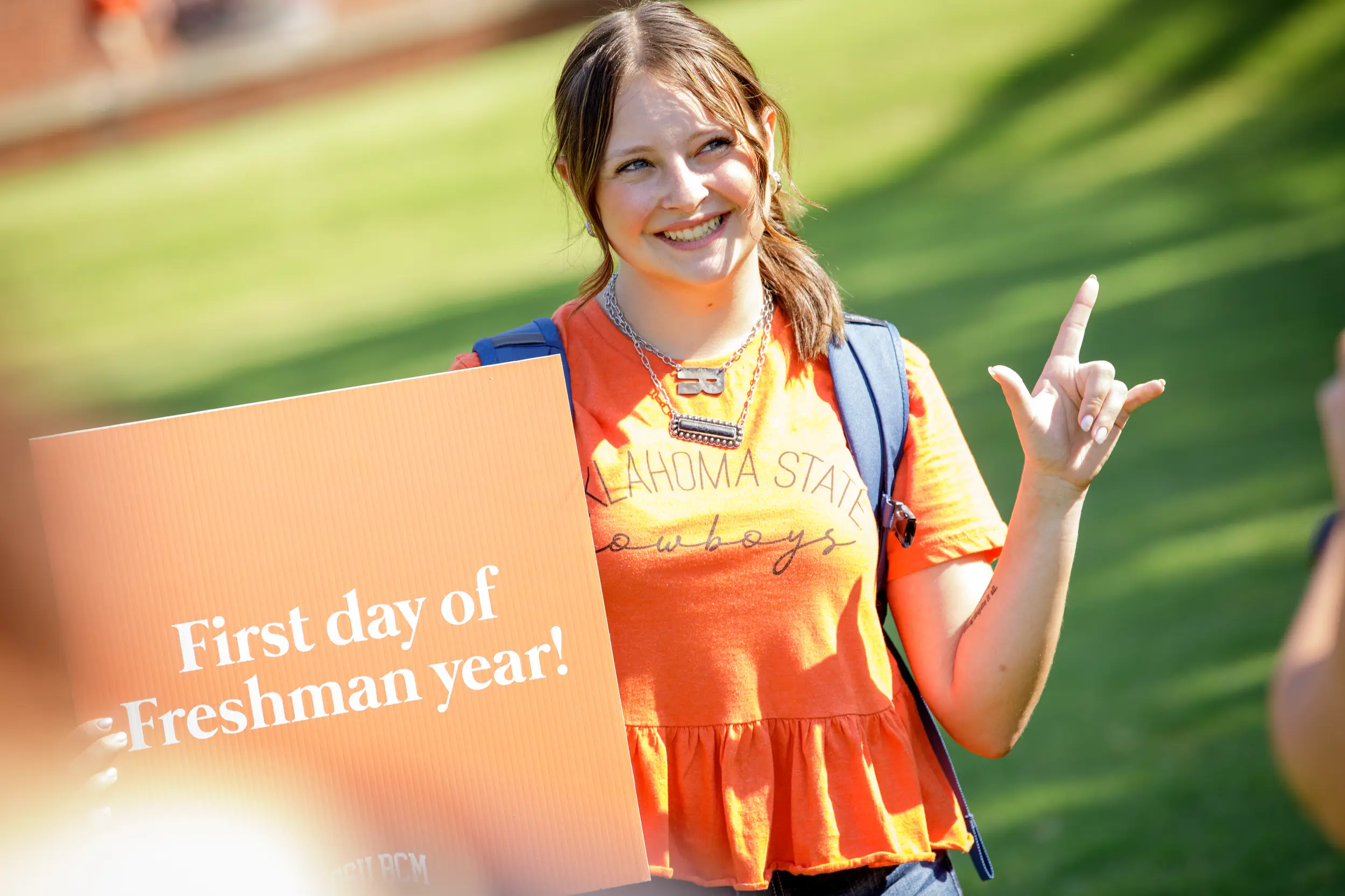 Smiling student holds up sign "first day of freshman year".